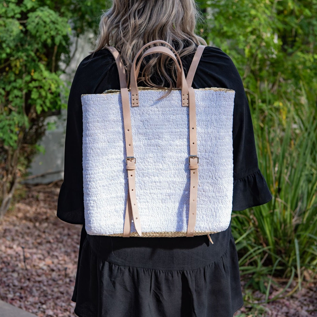 Woman wearing straw backpack with white sequins 