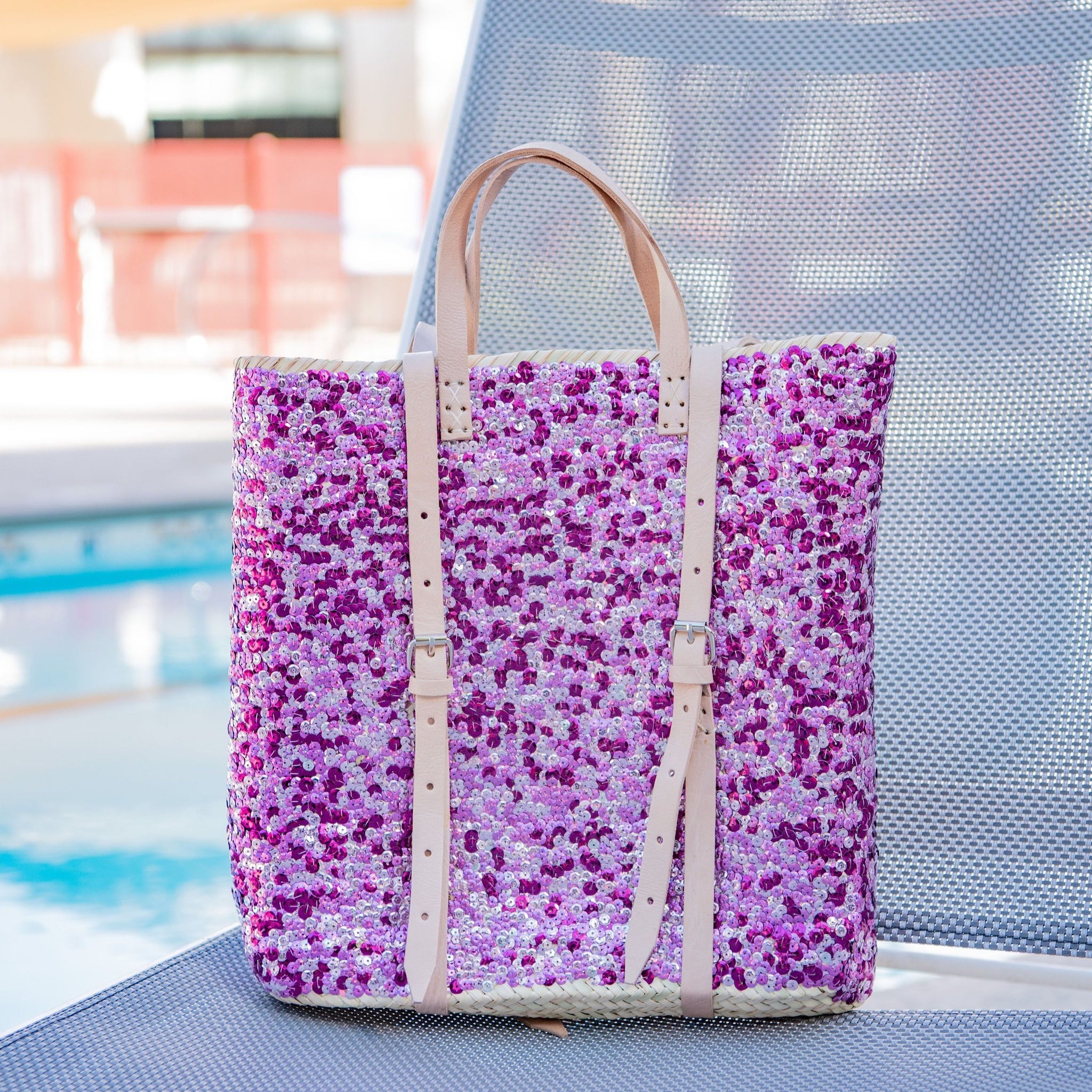 Straw backpack with purple sequins sitting on pool chair