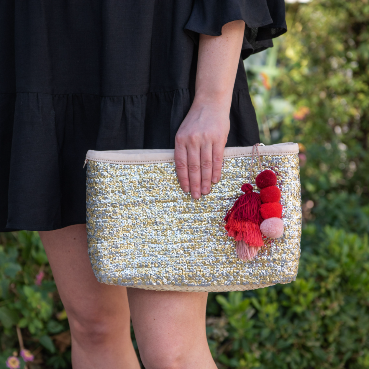 Woman holding straw clutch with silver and gold sequins