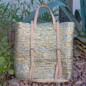Straw Backpack with Silver and Gold Sequins sitting against plants
