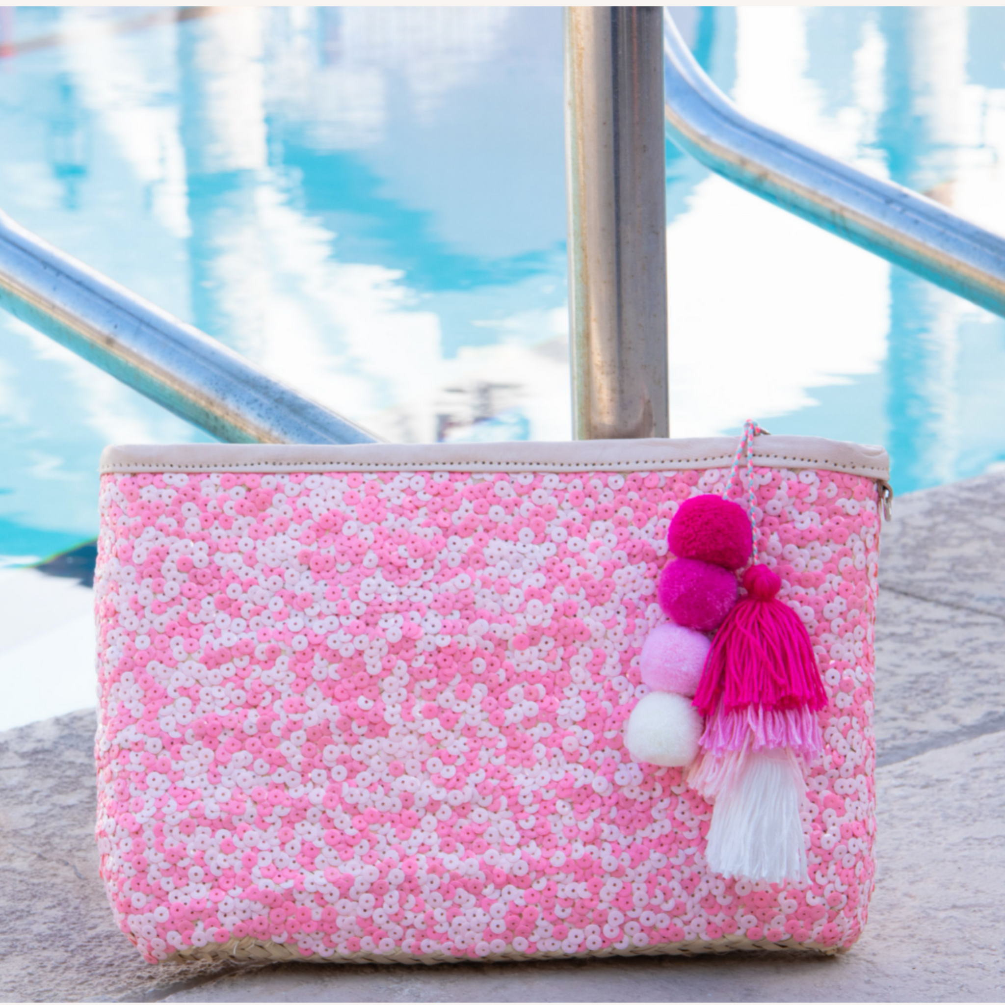 Straw clutch with pink sequins sitting next to pool