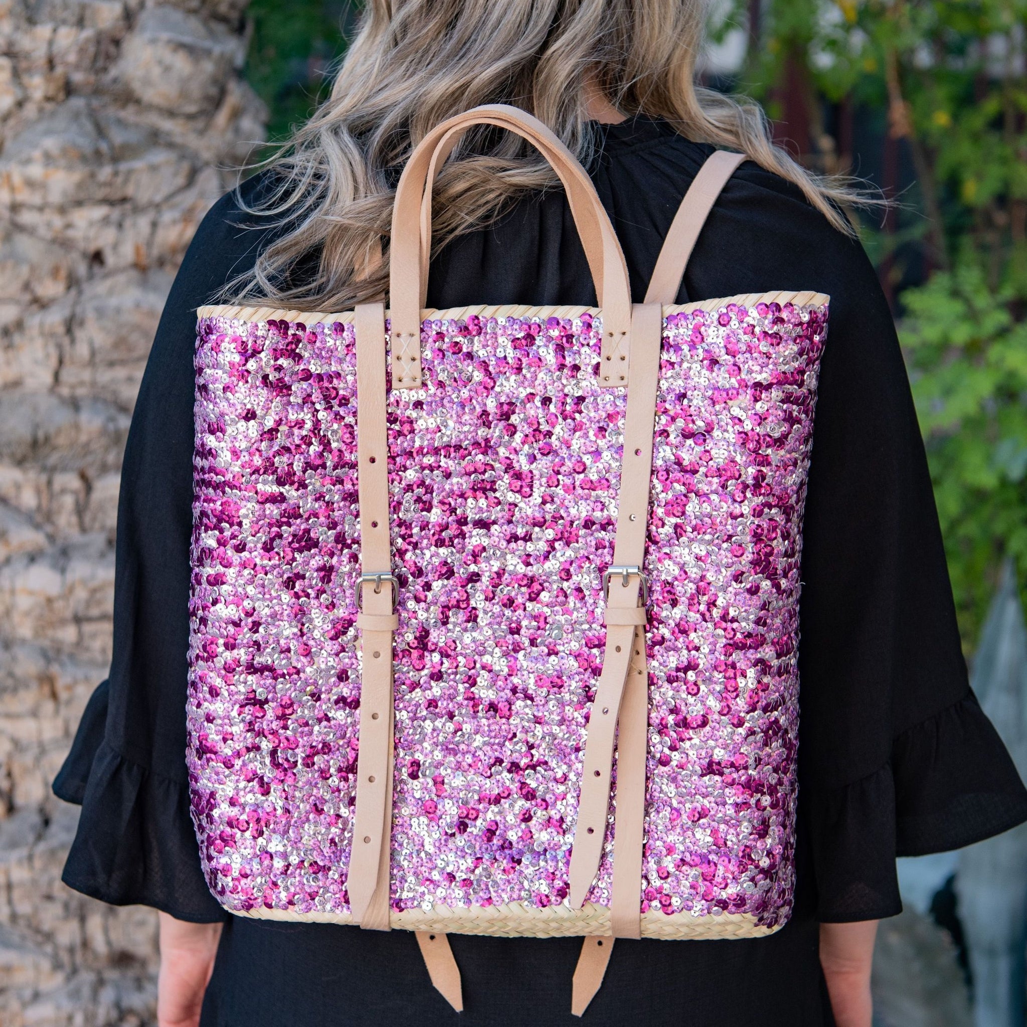 Woman wearing straw backpack with purple sequins