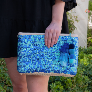 Woman holding straw clutch with blue sequins