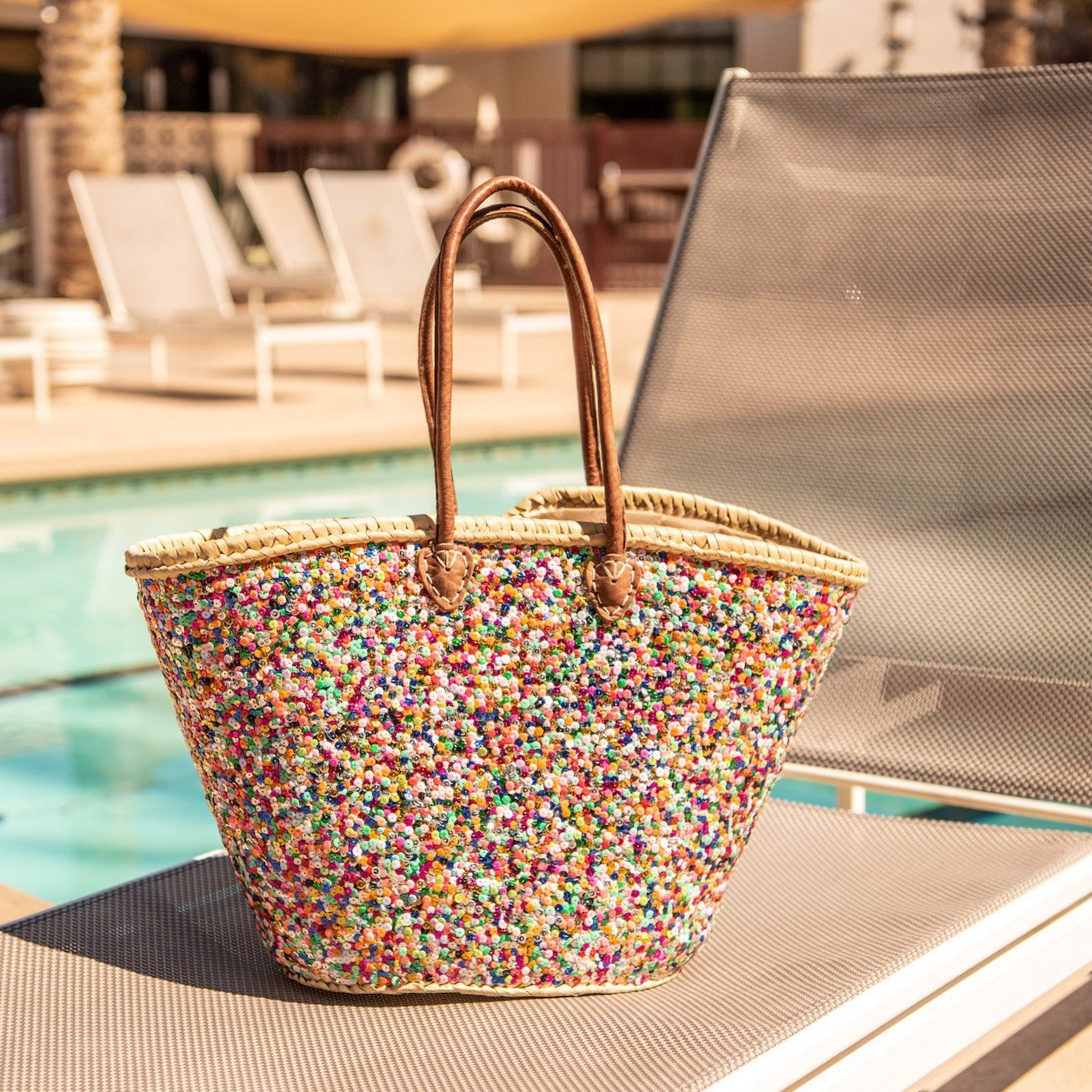 Large Straw Shoulder Bag with Multi-Colored Sequins sitting on pool chair