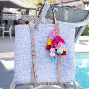 Straw backpack with white sequins hanging on back of pool chair